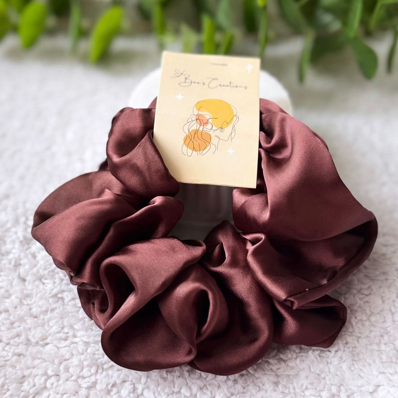 Brown satin scrunchie with a card on a textured surface