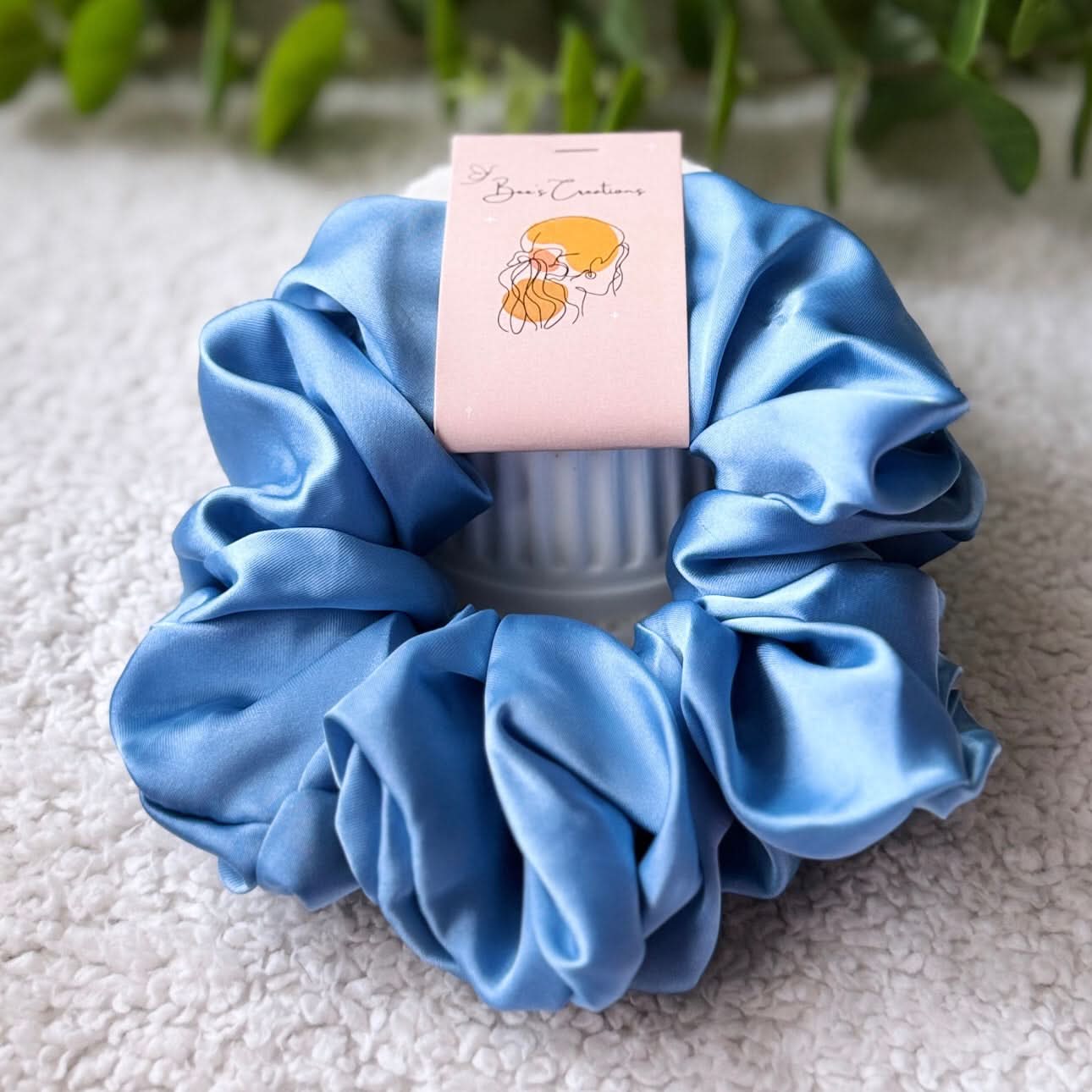 Blue scrunchie with a pink card on a textured surface