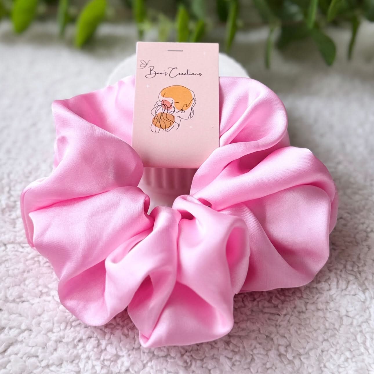 Pink scrunchie with a card on a textured surface