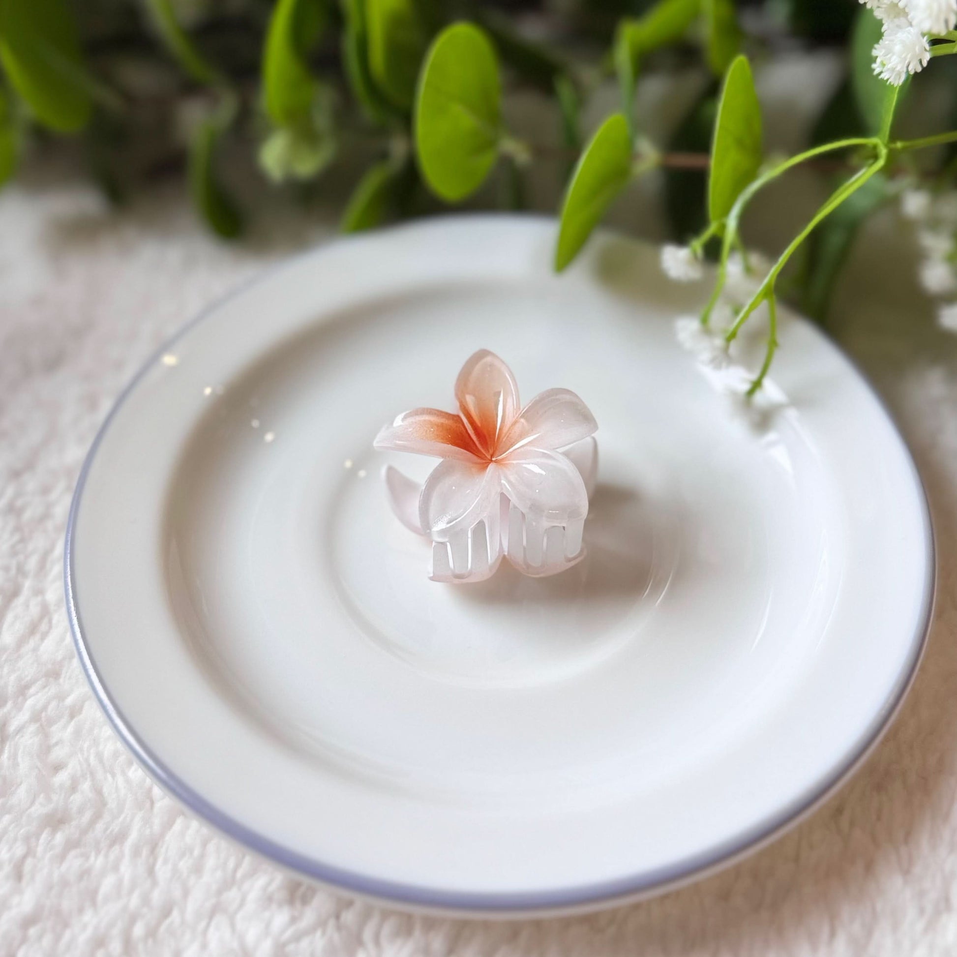 Pink flower-shaped object on a white plate with greenery in the background