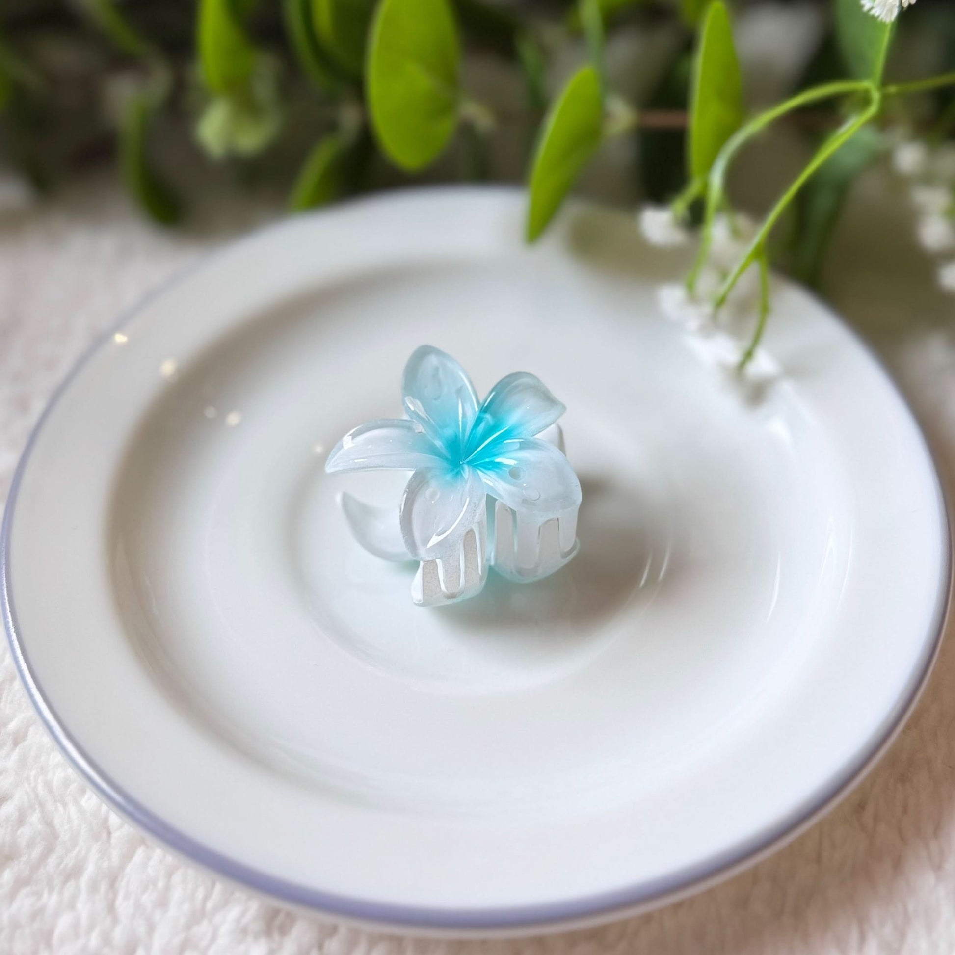 Blue butterfly-shaped object on a white plate with green leaves in the background