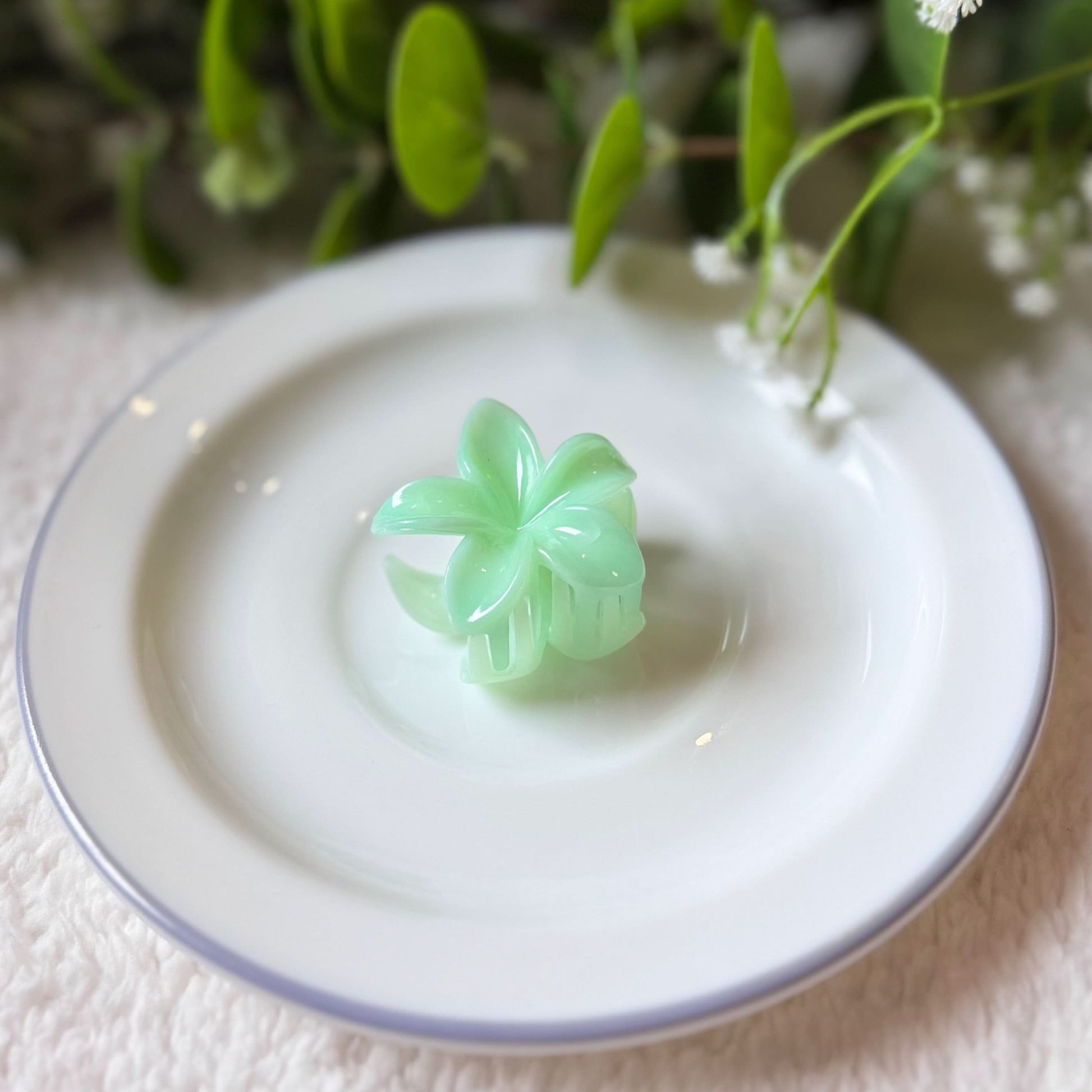 Green butterfly-shaped object on a white plate with greenery in the background