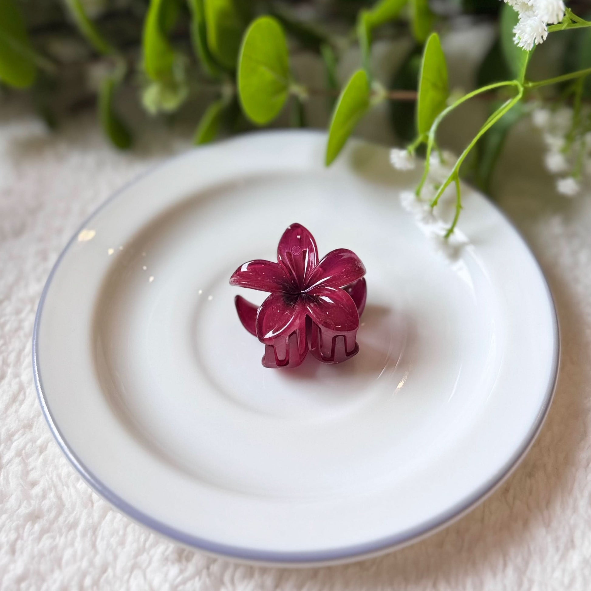 Purple flower-shaped object on a white plate with greenery in the background