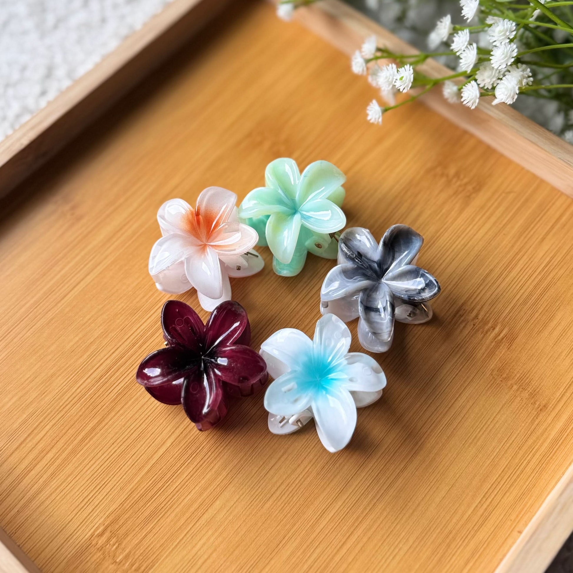 Colorful flower-shaped hair clips on a wooden surface with a blurred background