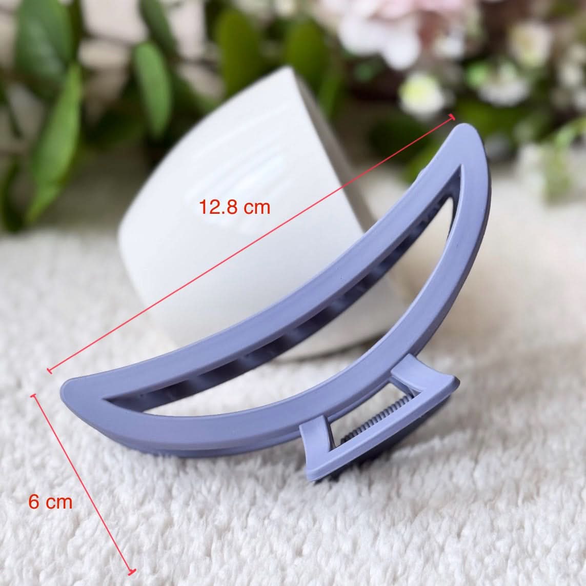 Blue hair clip with measurements on a white surface