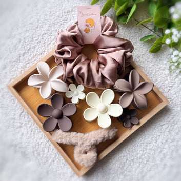 Set of scrunchies and floral hair accessories on a wooden tray with a light background