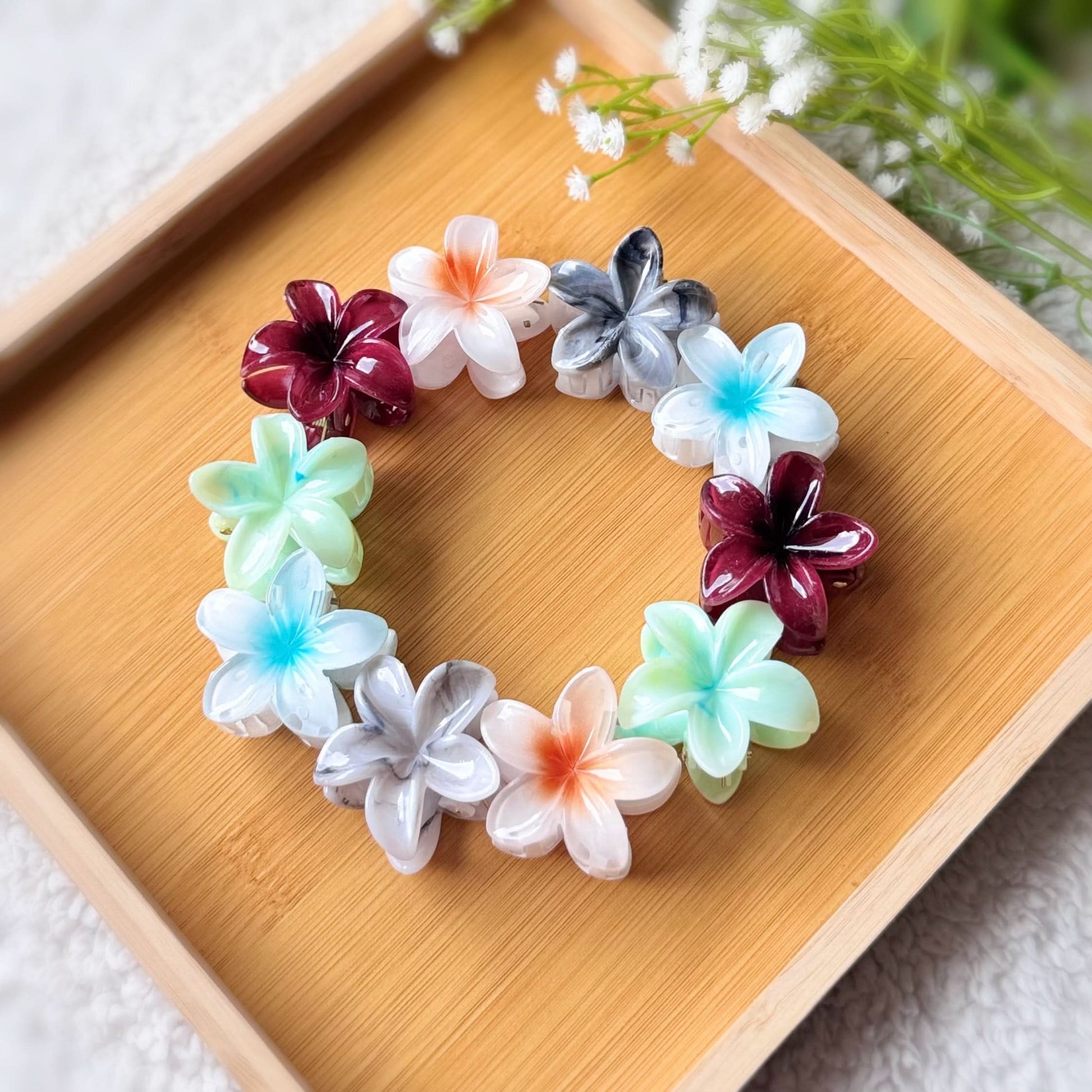 Colorful flower-shaped hair ties arranged in a circular pattern on a wooden tray.