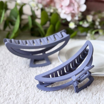 Two blue hair clips on a textured surface with flowers in the background