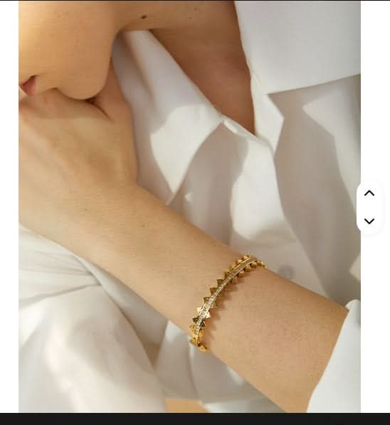 Gold bracelet on a wrist with a white fabric background