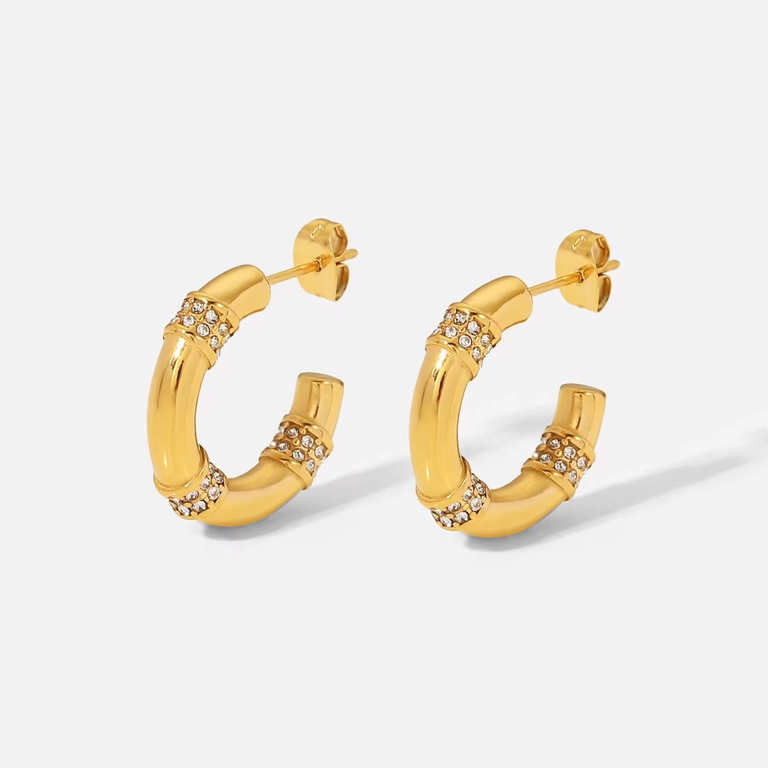 Gold hoop earrings with embedded stones on a light gray background
