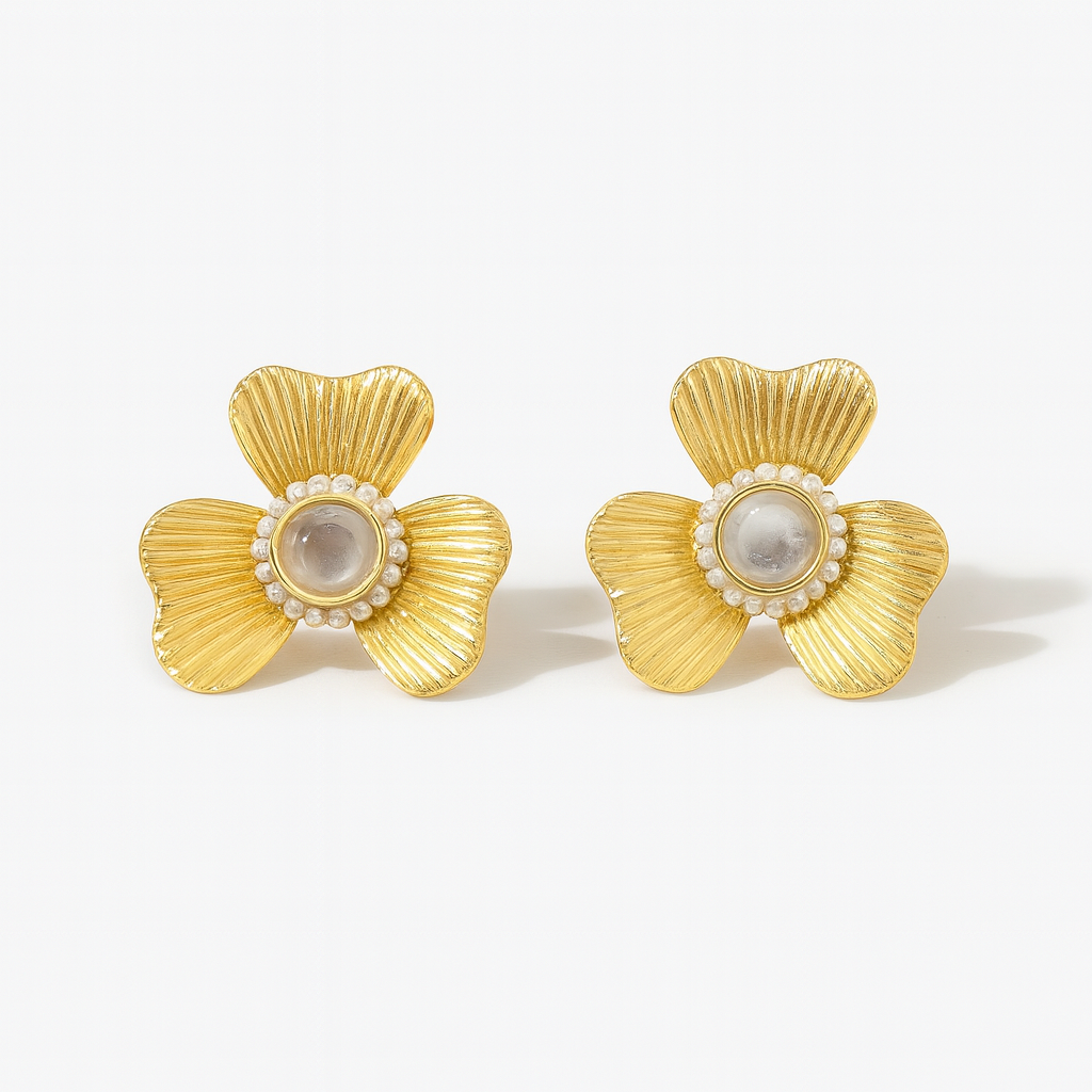 Pair of gold earrings with pearl center on a white background