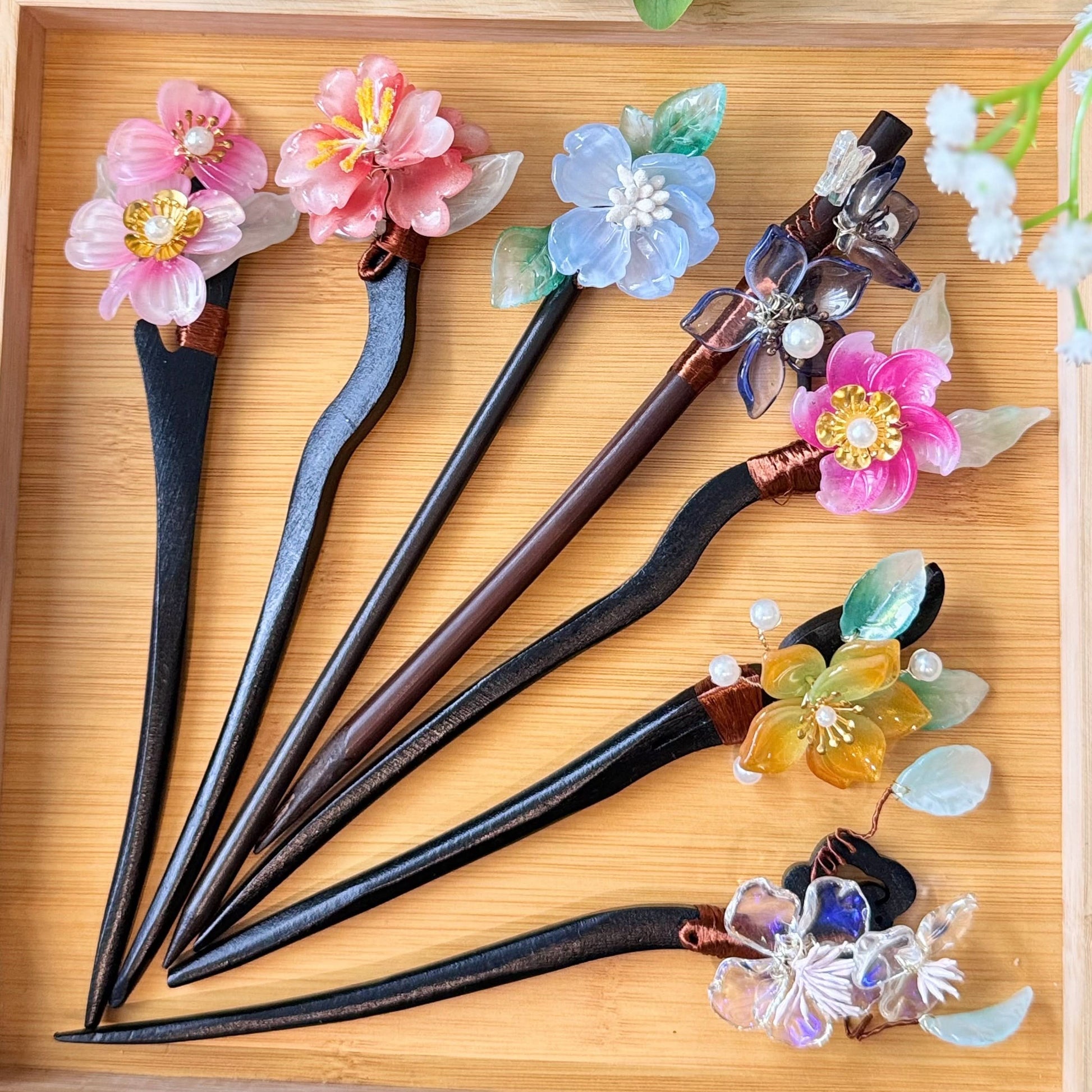 Set of decorative hair sticks with floral designs on a wooden surface