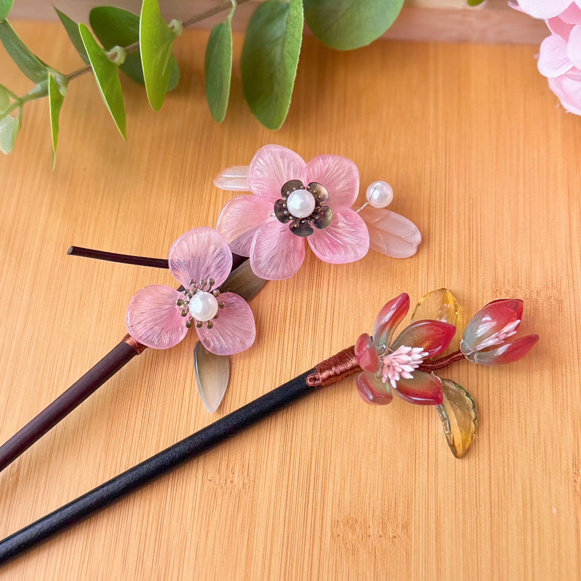 Decorative hair sticks with floral designs on a wooden surface