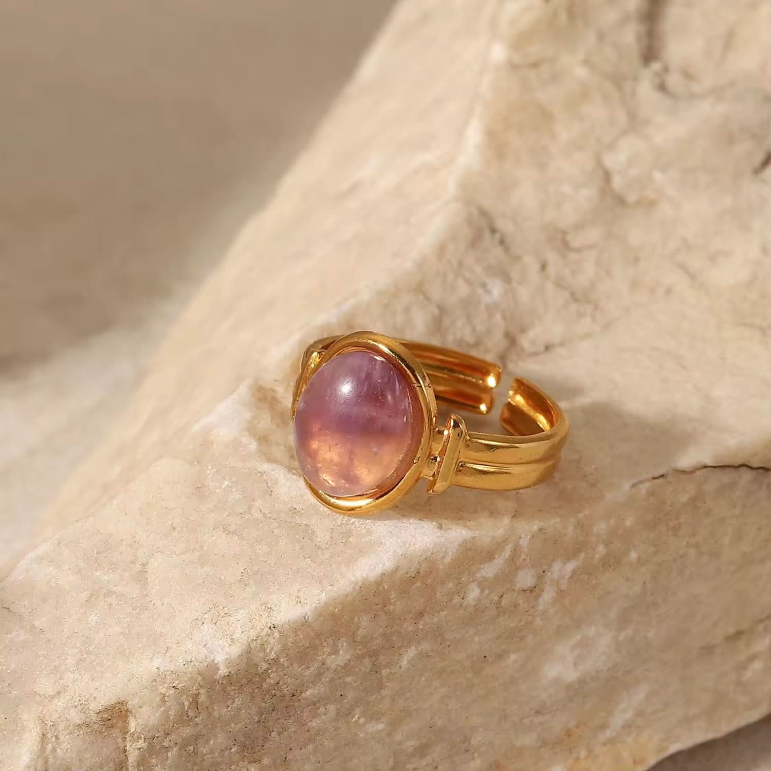 Gold ring with a pink gemstone on a stone surface