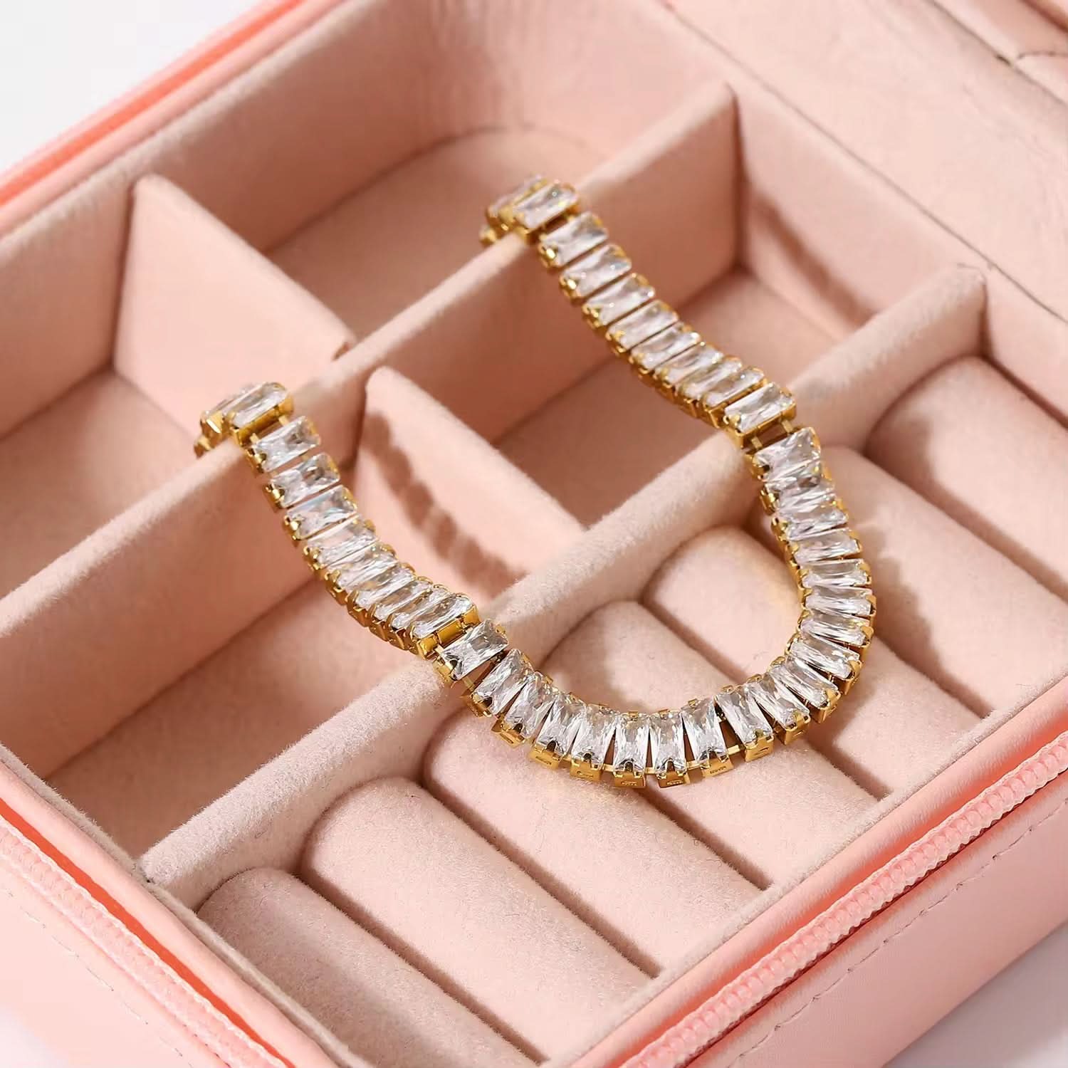 Gold and crystal hoop earring on a pink jewelry box