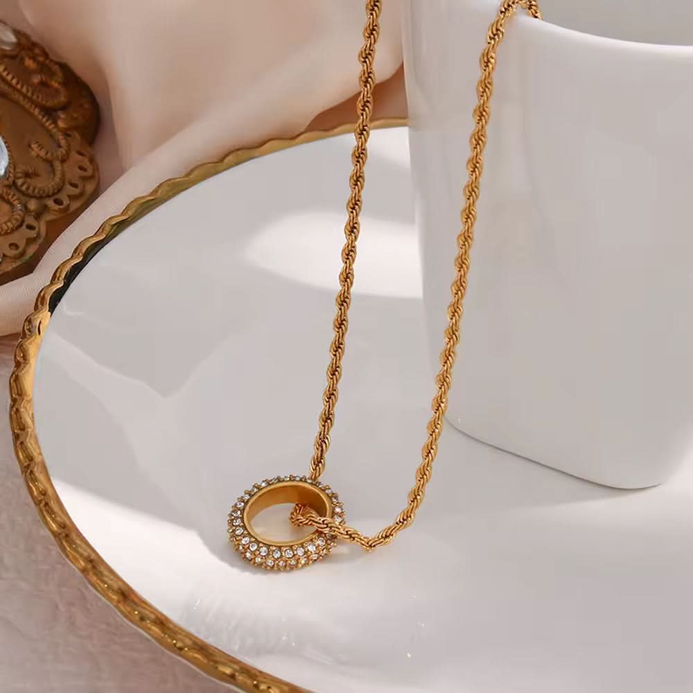 Gold necklace with a circular pendant on a white surface