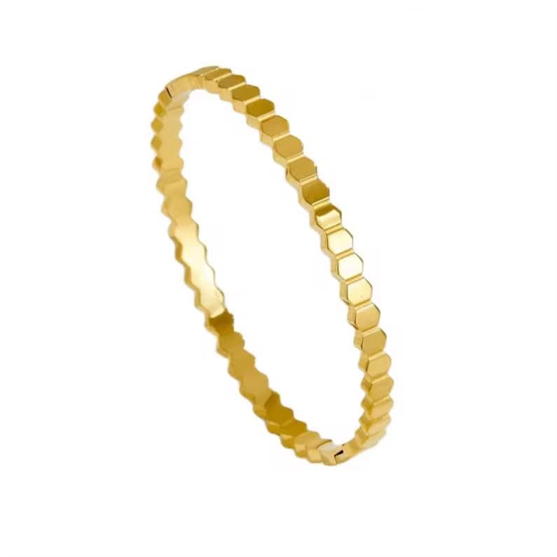 Gold bracelet with a honeycomb pattern on a white background