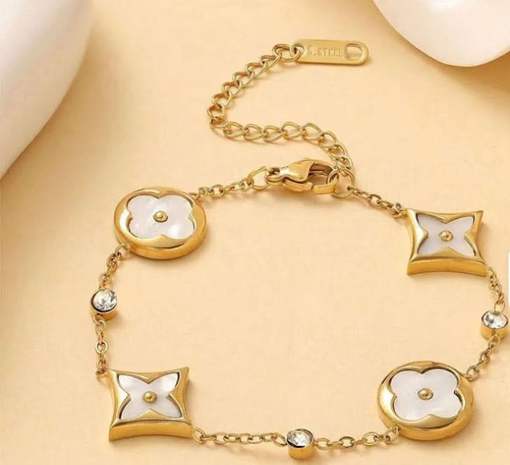 Gold bracelet with white floral designs on a beige background
